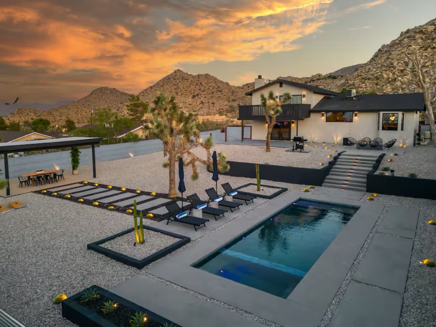 A desert modern home with a pool under a sunset sky