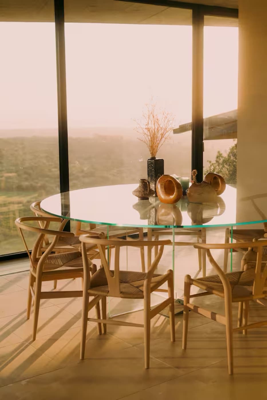 Golden hour through floor-to-ceiling glass over a round dining table