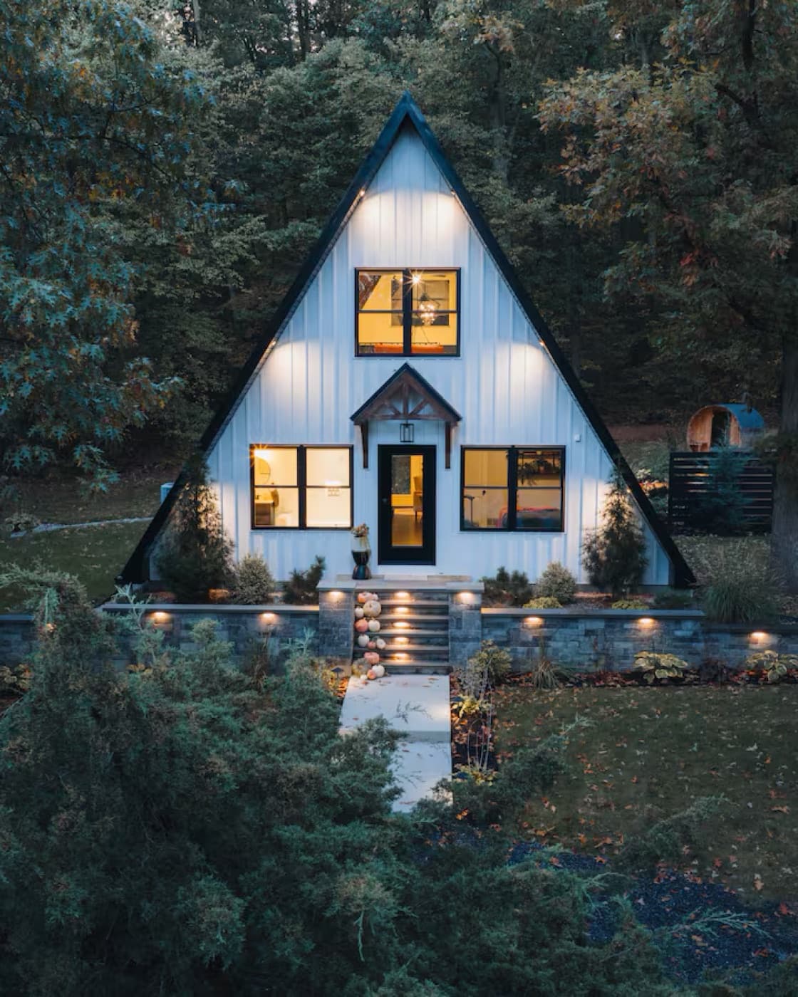 A lit A-frame cabin in deep woods at dusk