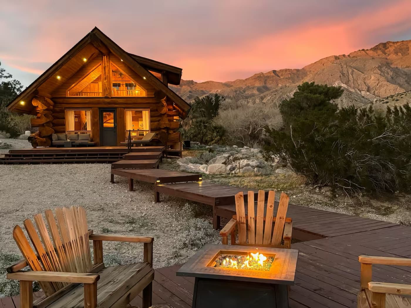 A log cabin and firepit under a desert sunset